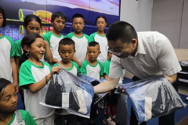 A staff worker of the uniform garment company of China Railway Hi-Tech Industry Co., Ltd. presents clothes to visiting students.